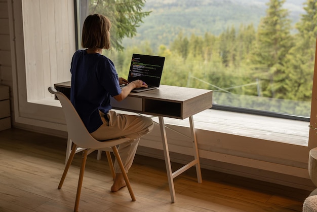 Woman works on laptop remotely in house on nature