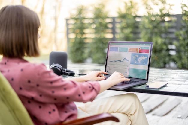 Woman works on laptop while sitting by the table outdoors