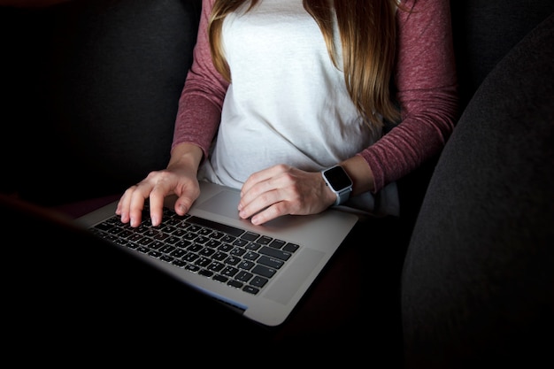 Woman works late sitting on the sofa with laptop