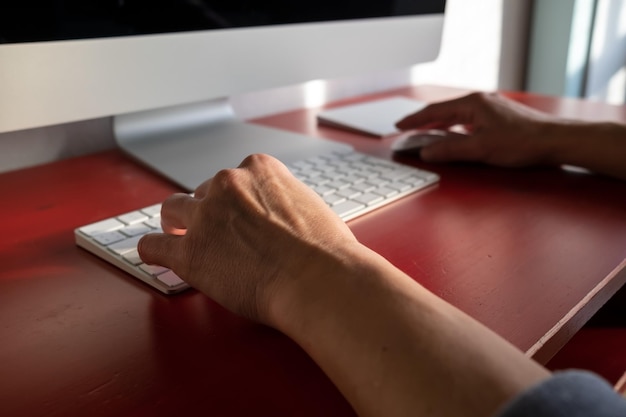 Woman works with a computer one hand is on the keyboard the other on the mouse