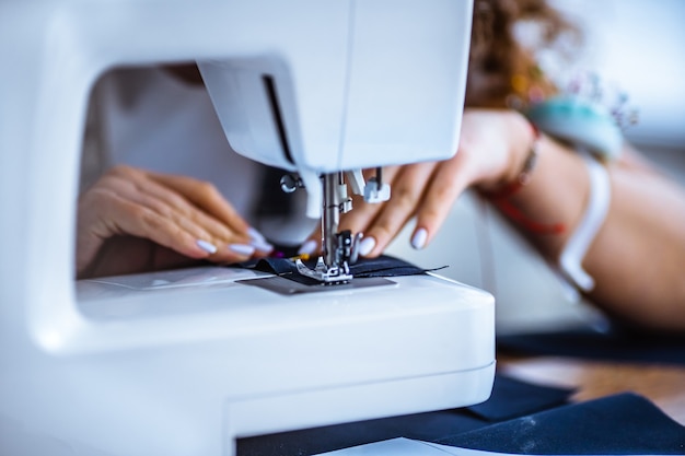 The woman works with a piece of cloth on the sewing machine