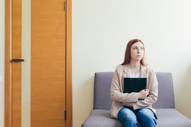 Woman worried in the waiting room corridor, fills out questionnaire tests