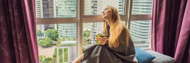 Woman wrapped in a blanket and looking at the big city banner long format