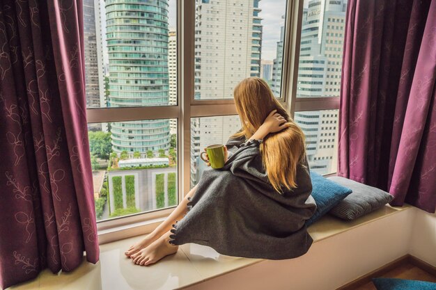 Woman wrapped in a blanket and looking at the big city