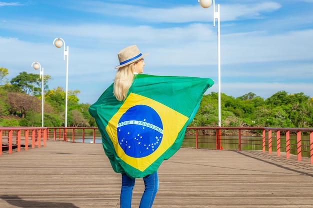 帽子とジーンズを身に着けているブラジルの国旗に包まれた女性