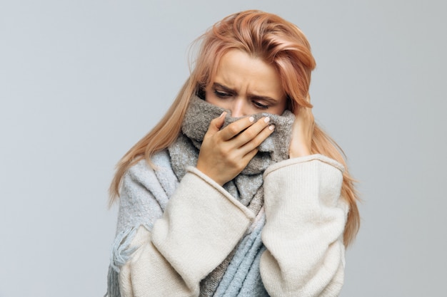 Фото Женщина, завернутая в теплый шарф, смотрит вниз, closeup.flu сезона