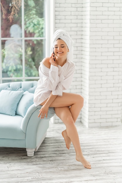 woman wrapped in a shower towel using mobile phone