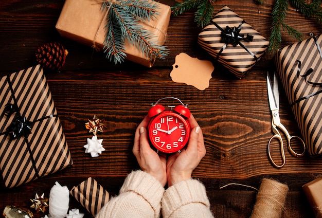 Woman wrapping an alarm clock as a gift on a table