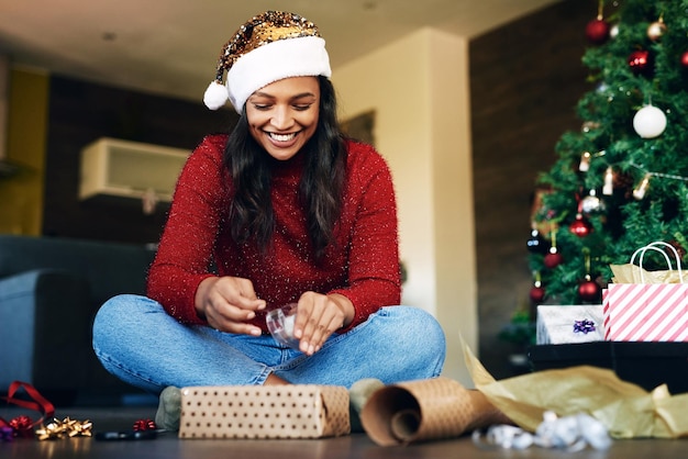 テープとギフト ボックスの休日のお祝いと幸福でクリスマスのギフトをラッピングする女性リビング ルームの床に幸せな女リボンと紙を提示笑顔し、家族の家で祝う