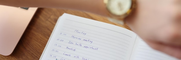 Photo woman write down plan for day look at wristwatch to check time