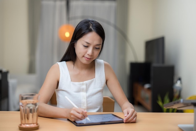 Женщина пишет на планшетном компьютере дома