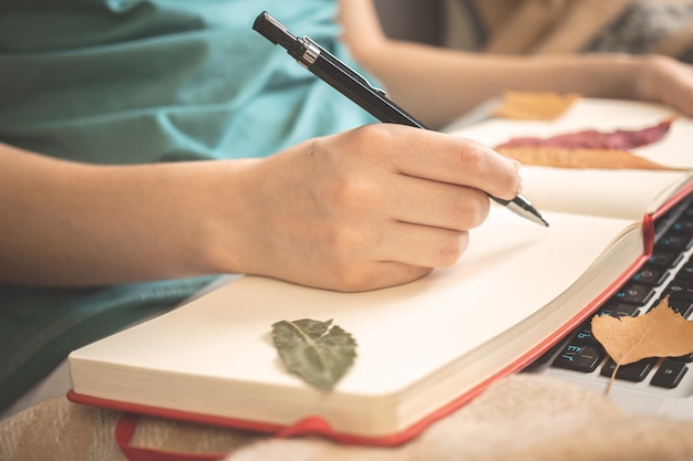 Woman writes ideas in own diary notebook sitting at home in autumn holidays, cozy autumn background photo