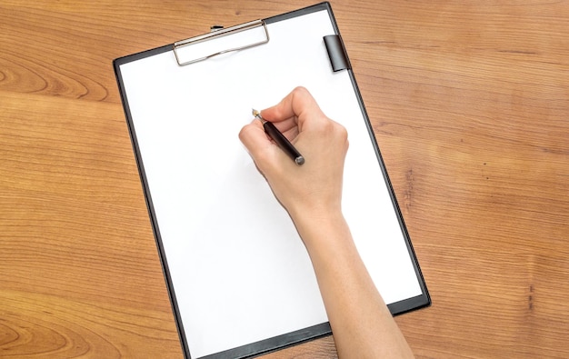 Woman writing on a blank sheet on a clipboard