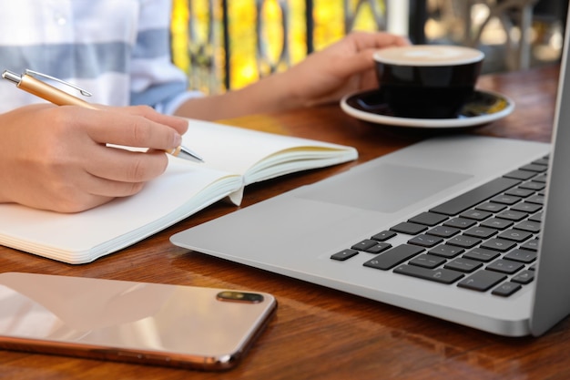 Woman writing blog content in notebook at table closeup