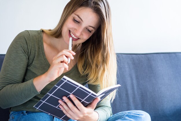 Woman writing on couch at home