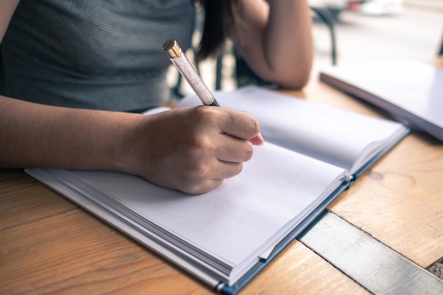 写真 コーヒーショップでノートに自分のアイデアを書いている女性