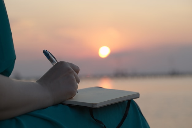 Woman writing in her diary at sunset