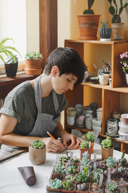 写真 甘い植物の苗にラベルを書く女性