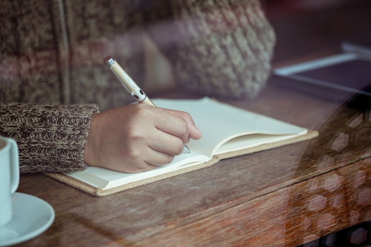 Photo woman writing on notebook in a cafe in rainy day. vintage color tone