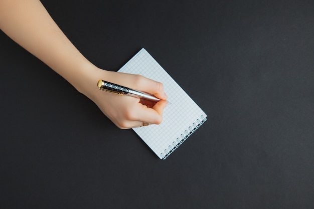 Woman writing in notepad at black table