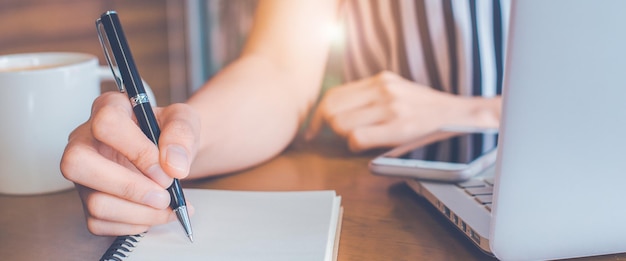 Foto scrittura della donna su un blocco note con una penna in ufficio