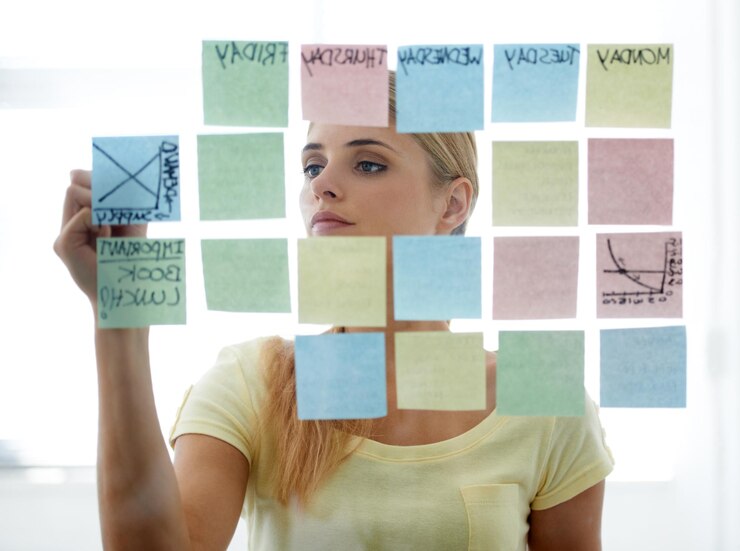 Photo woman writing on sticky notes and glass wall with schedule serious and planning copywriter brainstorming and office job with calendar workplace and moodboard for ideas content plan and creative