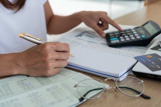 Woman writing and using calculator, account and saving concept.