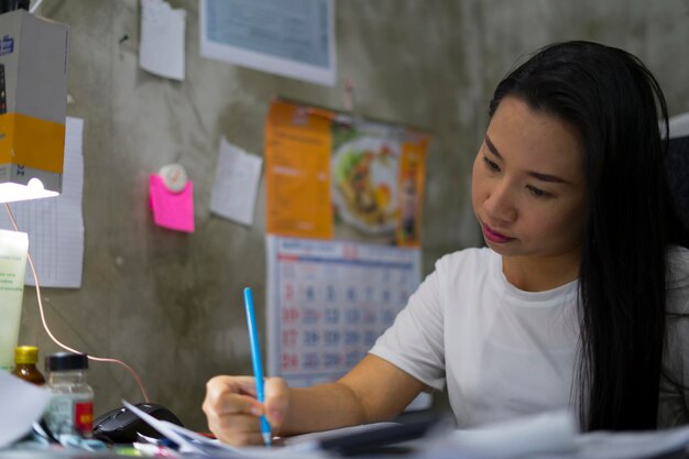 Photo woman writing while sitting by table at home