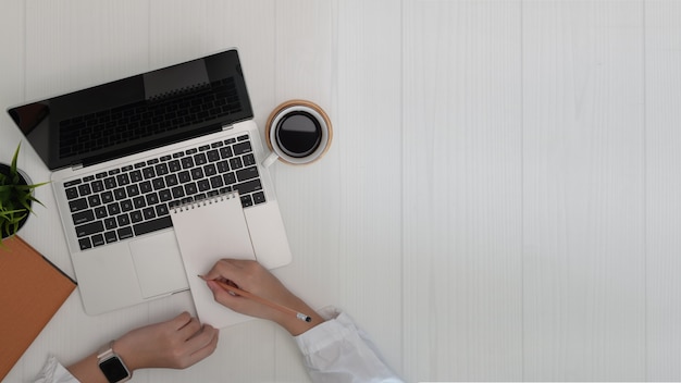 Woman writing and working on laptop. Business and copy space background