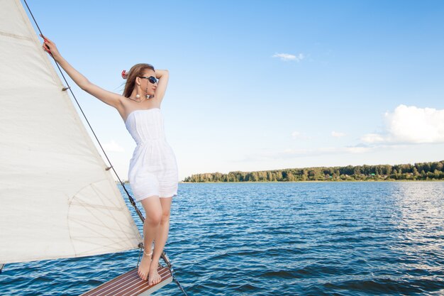 白い海と帆のスペースに対するヨットの女性