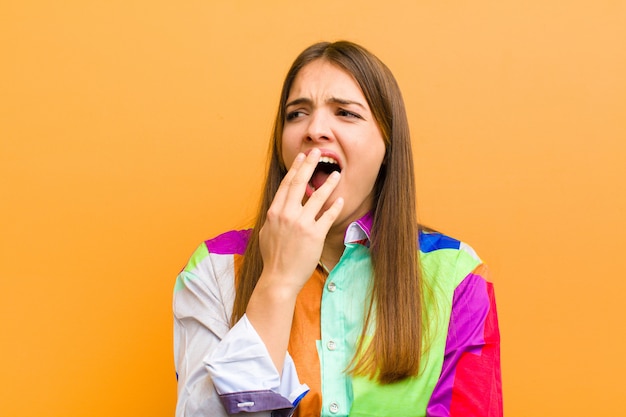 Donna che sbadiglia pigramente la mattina presto, svegliarsi e sembrare assonnata, stanca e annoiata