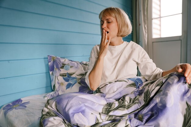 A woman yawns in bed in the bedroom