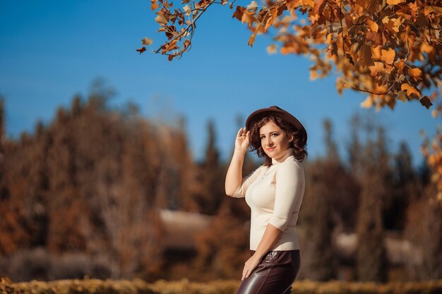 Woman years old in a brown hat in the fall for a walk in the park