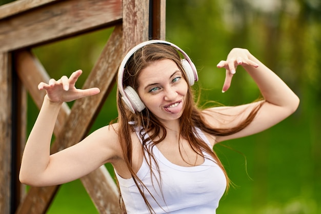 Woman  years old in wireless headphones is grimacing in park