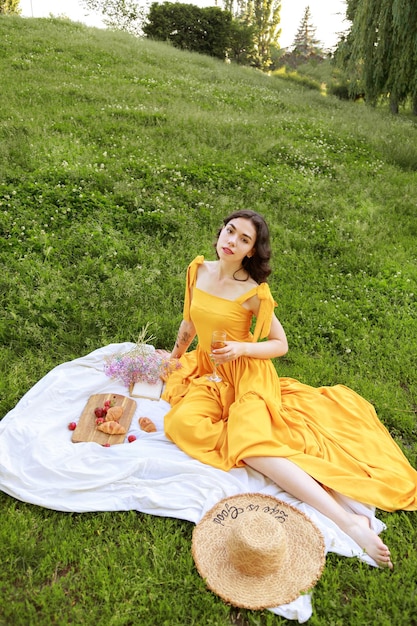 A woman in a yellow dress at a picnic in the garden in the\
summer