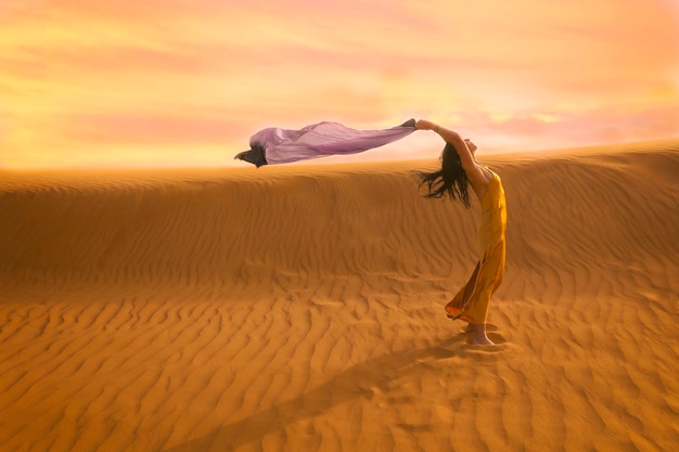 woman in yellow dress playing with the wind in the desert v