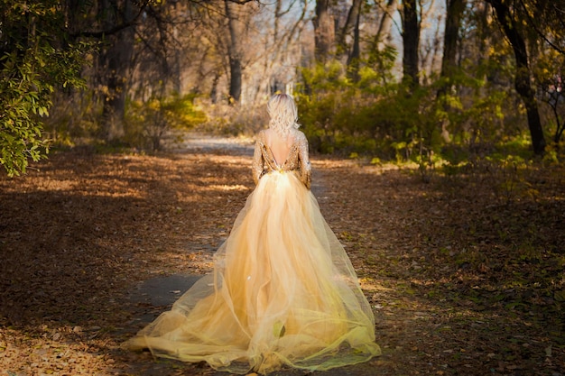 A woman in a yellow dress walks through a forest.