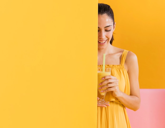 Foto donna in abito giallo con un bicchiere di succo