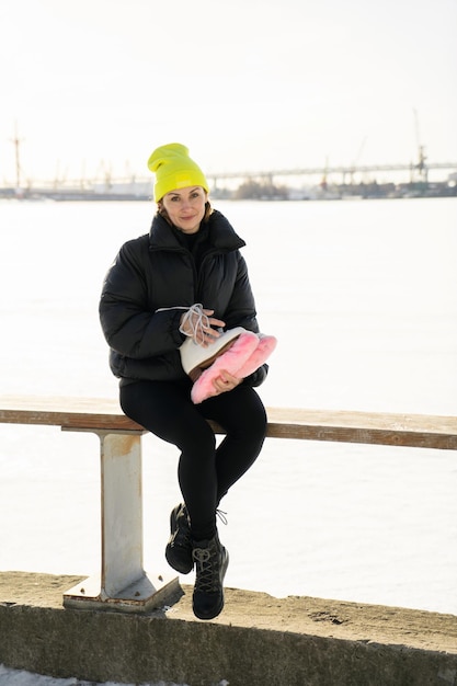 A woman in a yellow hat is skating on an ice rink in winter