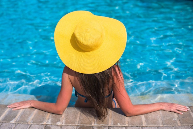 수영장에서 편안한 노란 모자에있는 여자