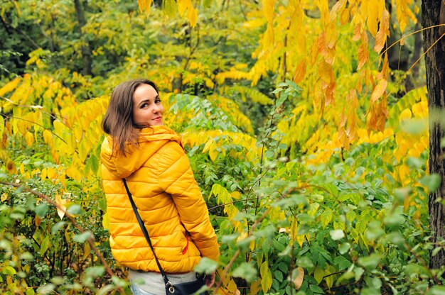 Woman in yellow hoody hiking in a forest.