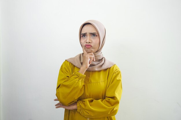 A woman in a yellow outfit with a yellow scarf and a tan scarf is looking at the camera.