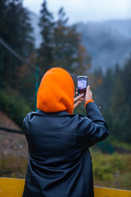 Woman in yellow raincoat hiker in autumn mountains copy space