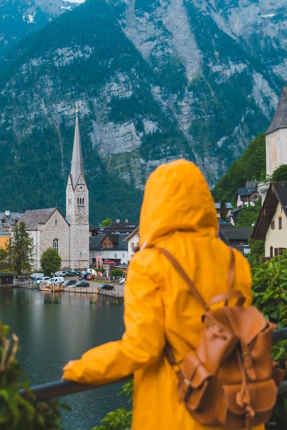 Woman in yellow raincoat looking at hallstatt city