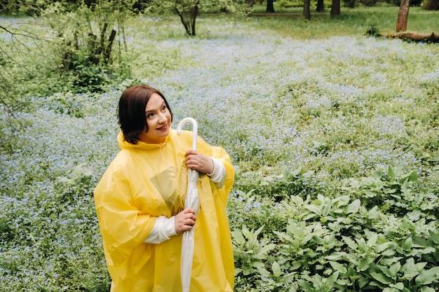 A woman in a yellow raincoat walks in the park and garden in the summer.