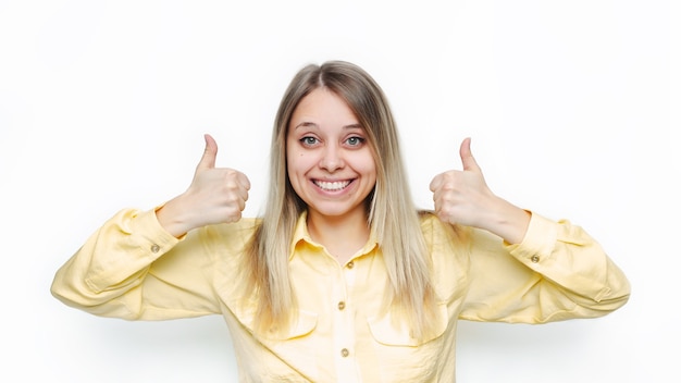 Foto donna in una camicia gialla che mostra i pollici aumenta il gesto