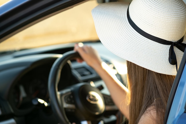 Woman in yellow straw hat sitting behind steering wheel