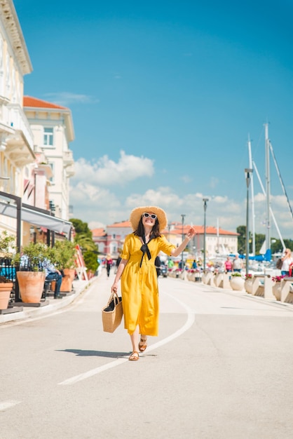 Woman in yellow sundress walking by resort summer city