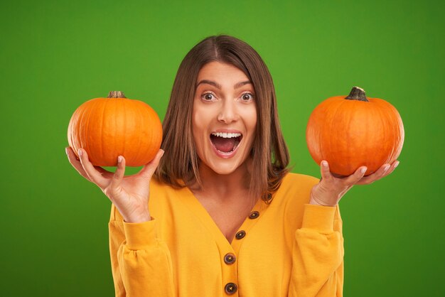 woman in yellow sweater holding pumpkin over green background