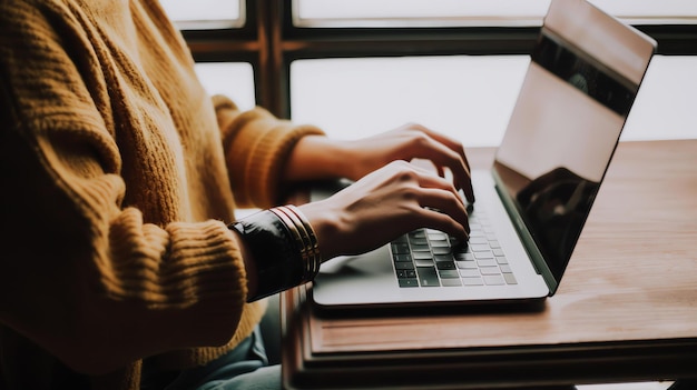 Photo a woman in a yellow sweater is working on her laptop she has two bracelets on her right wrist the laptop is placed on a wooden table